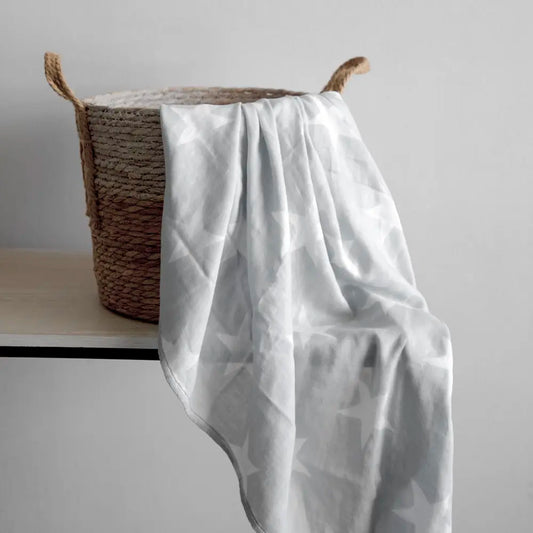 Manta Swaddle Bambú Gris - Kosleeping sobre canasto de mimbre sobre mesa