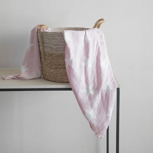 Manta Swaddle Bambú Rosada - Kosleeping sobre canasta mimbre en una mesa