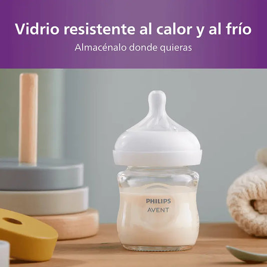 Mamadera Philips Avent Natural Response 120ml Vidrio con leche a un costado de juguetes con fondo gris